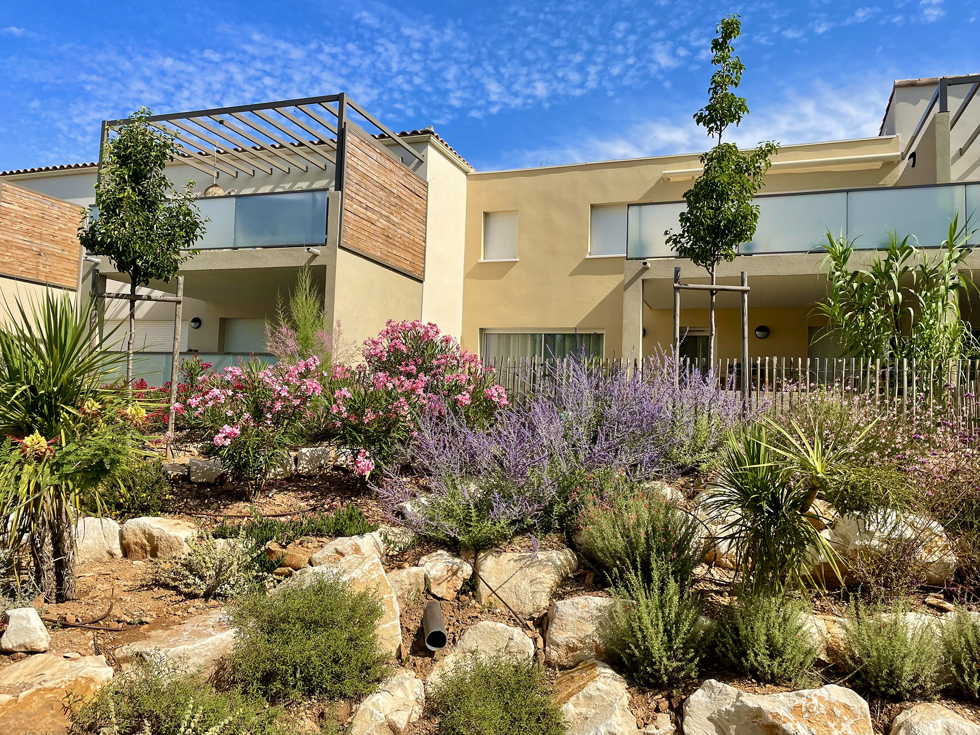 Façade moderne et jardin verdoyant du programme immobilier Côté Colline