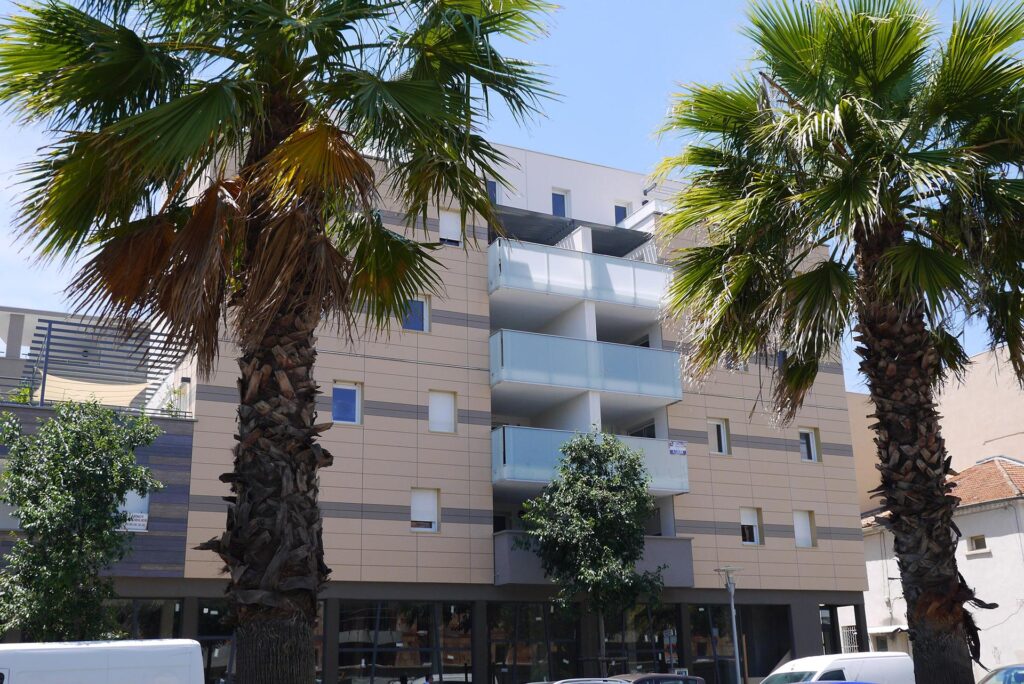 Vue de la façade avec palmiers du programme immobilier Carina à Nîmes